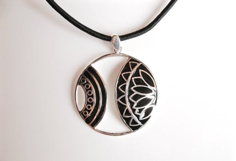 Artistic round pendant with cut outs and fine black enamel detailing