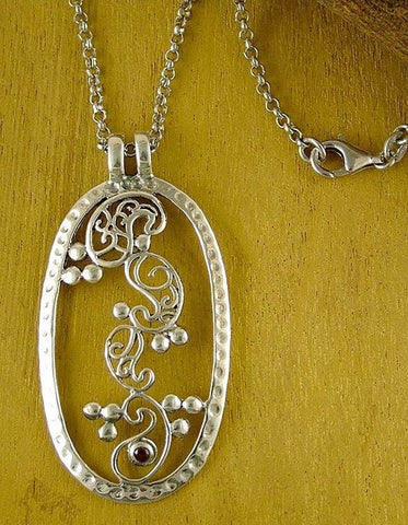 Elegant, oval pendant with four dancing paisley motifs and a garnet accent - Lai