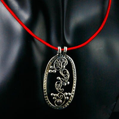 Elegant, oval pendant with four dancing paisley motifs and a garnet accent - Lai