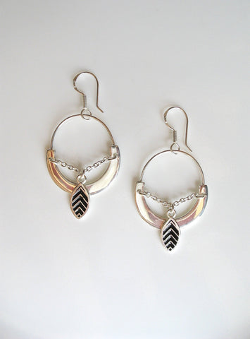 Unique, oval earrings with a dangling black enamel leaf charm